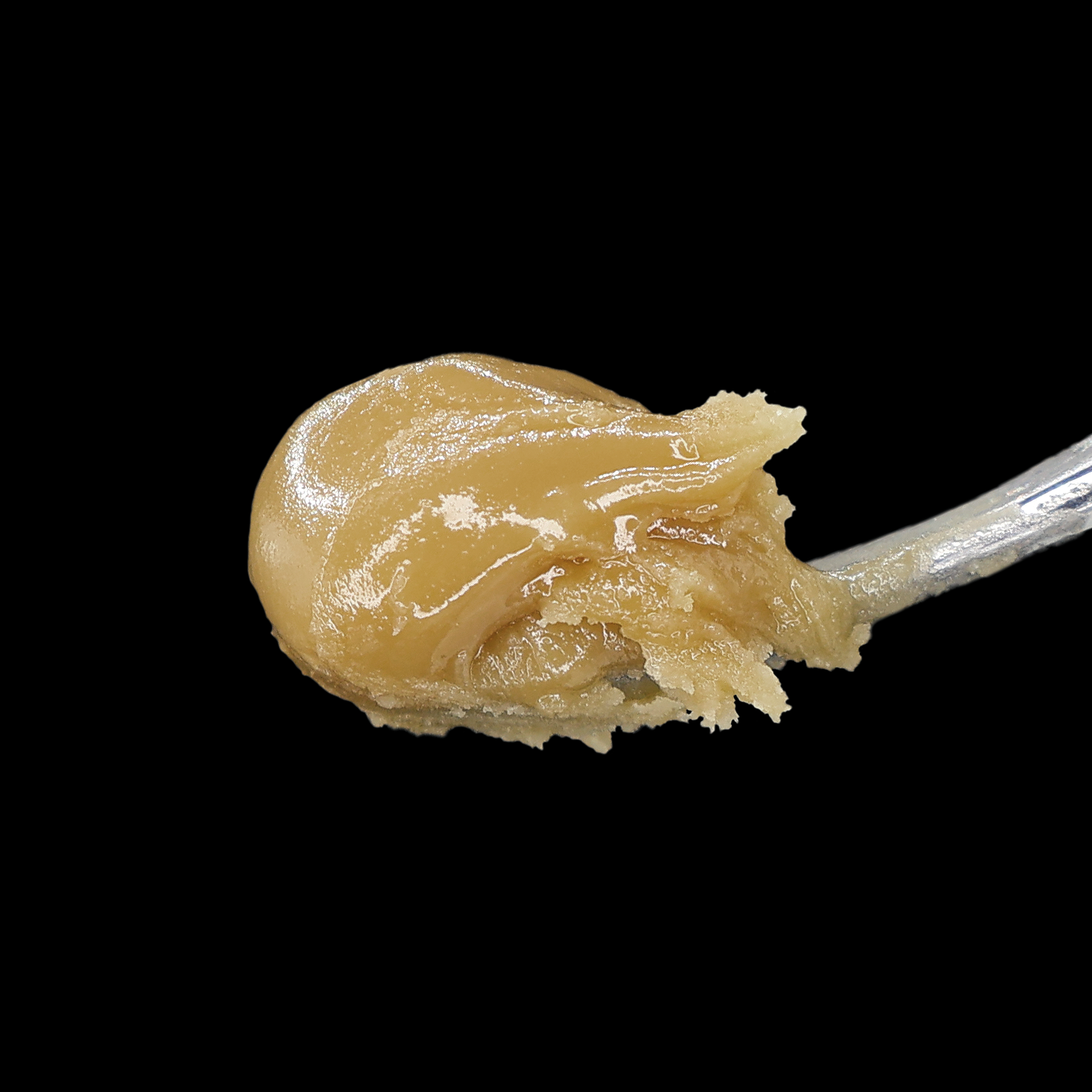 Sour Chem X OG 95 Hash Rosin by Miracle of The Desert, close-up of golden hash rosin in a jar with a textured surface.